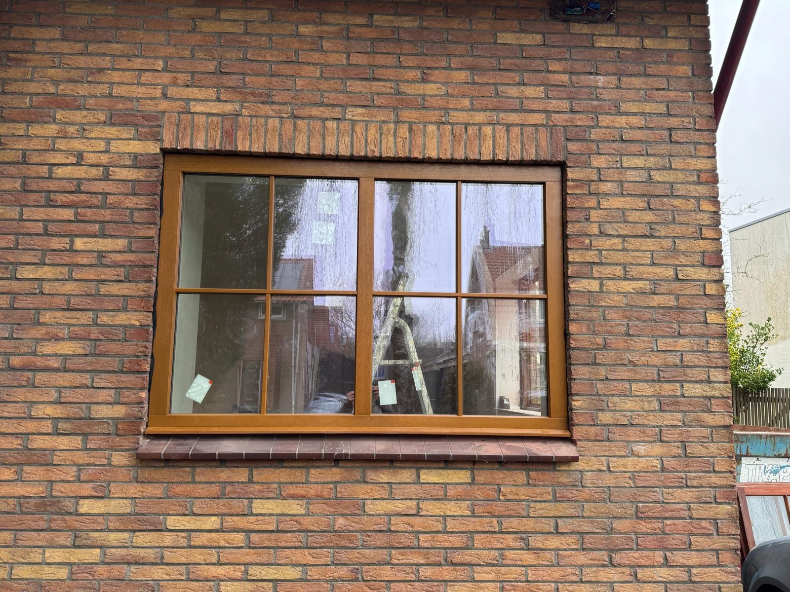 Geschilderde houten kozijnen in een bakstenen gevel